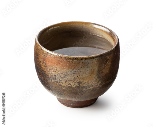 Traditional Japanese Bizen ware ceramic sake cup filled with sake isolated on white background