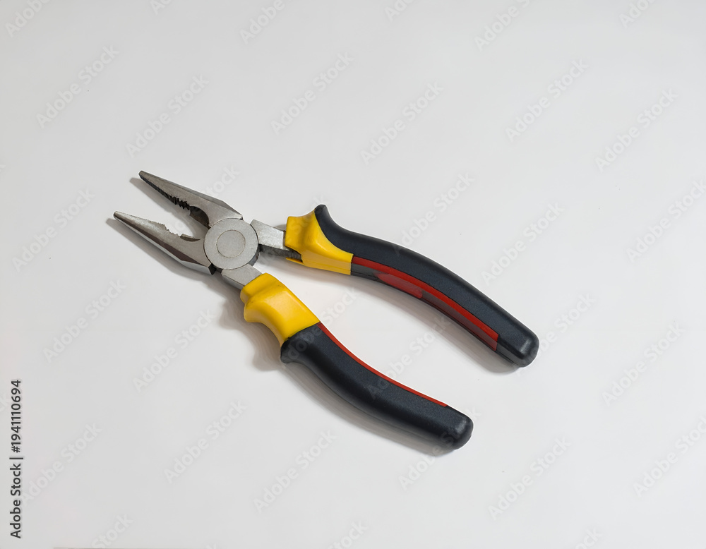 Fototapeta premium Metal pliers with yellow and black insulated grips, lying on white