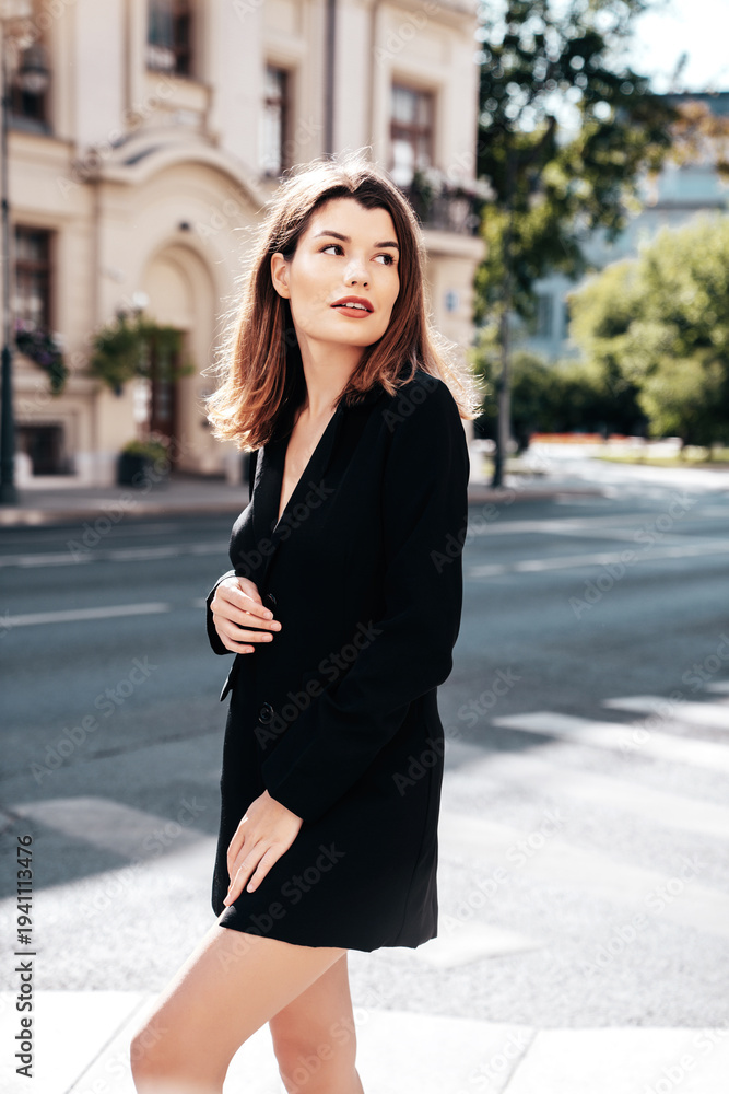 Fototapeta premium Portrait of young beautiful brunette woman wearing nice trendy suit black jacket clothes. Sexy smiling model posing in the street at sunny day. Fashionable female outdoors. Cheerful and happy