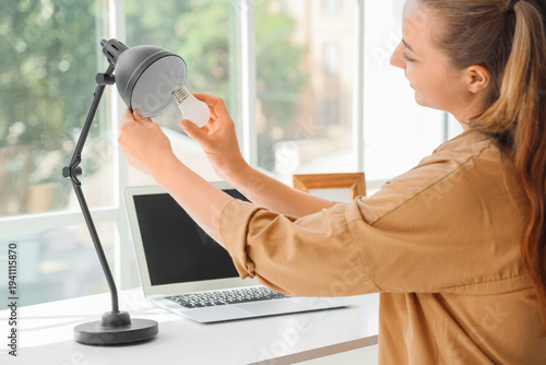 Young woman screwing light ...