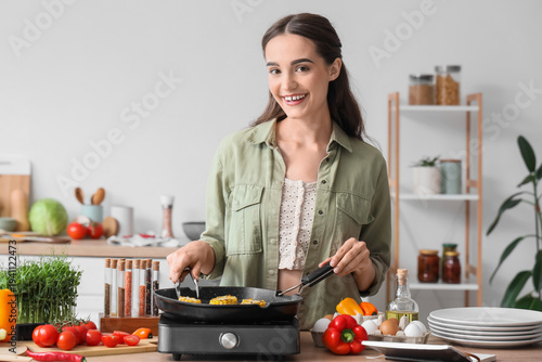 Young woman frying corn on ...