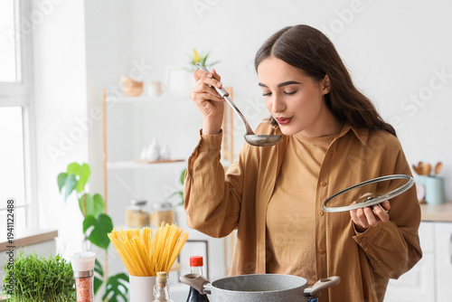 Young woman tasting soup in...
