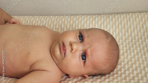 Canvas Print An intimate, close-up view of a newborn baby with bright blue eyes looking at the camera