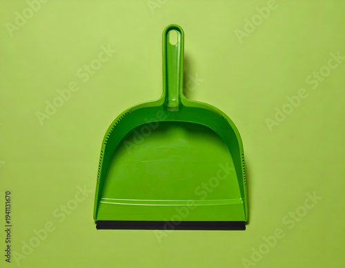Green dustpan with black rubber lip on plain light green background