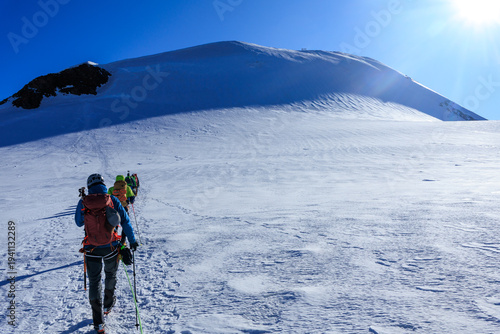 Quadro em tela Mountaineers in rope team with crampons ascending towards mountain summit Parrot