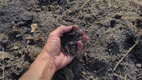 A slow-motion video footage showing hand scooping up and holding handful of dark fertile soil. Perfect for representing gardening organic farming and connection to the earth
