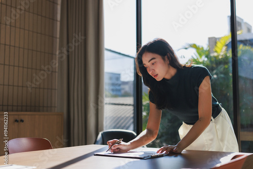 Free Download Young asian woman writing on clipboard in office - GFXLoad