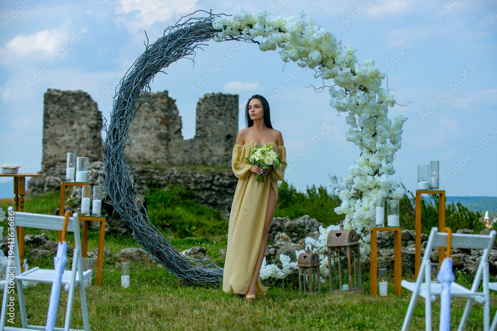 Fototapeta premium Elegant bride woman under wedding arch. Romantic wedding arch outdoor scene. Bride under floral wedding decor. Luxury wedding arch with flowers. Beauty bride ceremony concept.