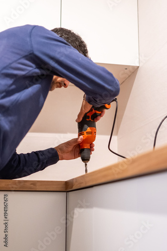 Wallpaper Mural Man using electric drill to assemble furniture and perform diy maintenance in a modern kitchen, focused on renovation tasks and home improvement projects at the countertop Torontodigital.ca