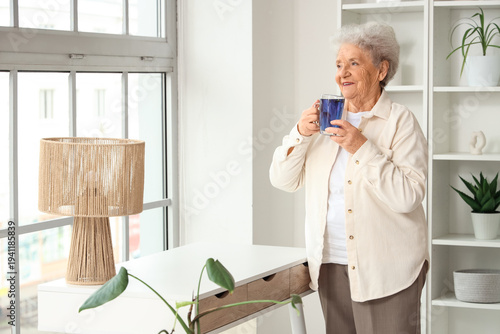 Senior woman with glass cup...