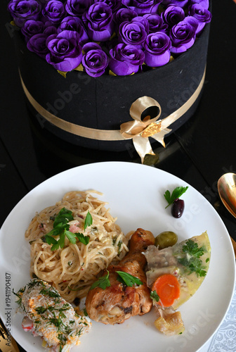 Spaghetti Carbonara, Hähnchen, Sülz und Oliven in weißem Teller mit blauen Rosen im Hintergrund