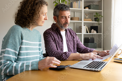 Couple planning family budget discussing finances using laptop