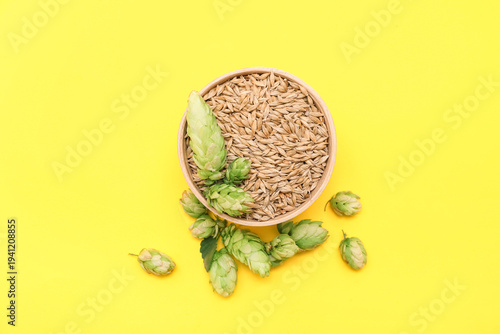 Fotografi Bowl with green hops cones and seeds on yellow background