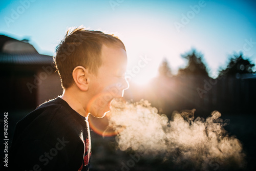 Playful boy blowing breath in winter air