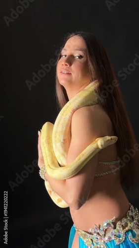 Belly dancer performs with a snake in a dimly lit studio