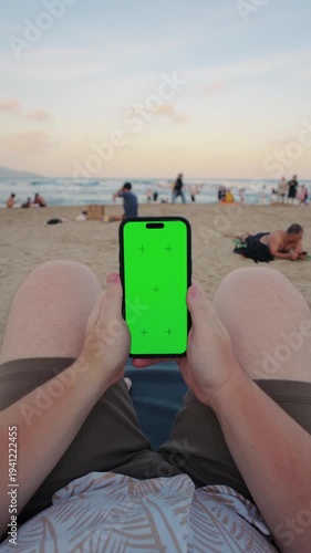 POV holding green screen smartphone on beach at sunset