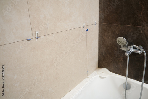 Schilderij op canvas Bathroom renovation with newly installed porcelain stoneware wall tiles above bathtub, using spacers and leveling clips before grouting