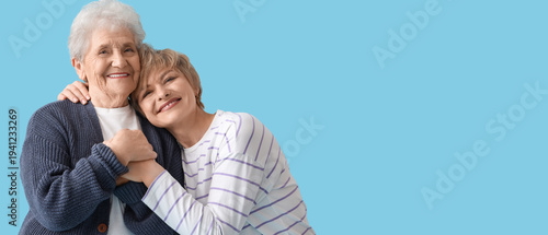 Mature woman with her mother hugging on blue background