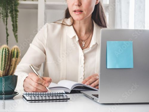 Fotografie Professional woman in a white blouse works as an administrative assistant with a laptop