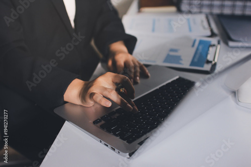 Auditors collaborating in modern office, analyzing financial documents and using calculator with a laptop displaying charts. Audit and taxes in business