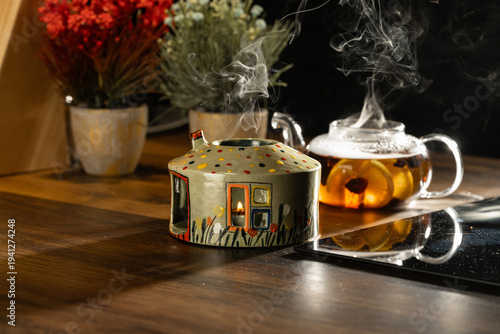 Cozy home tea ritual with steaming glass teapot, fresh lemon, apple, and decorative flowers on a wooden table