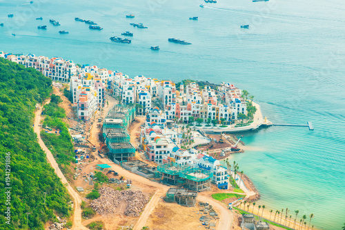 Aerial view of colorful seaside resort buildings under construction on coastline on Phu Quoc Island, Vietnam, along the Hon Thom cable car route. Coastal tourism development and urban expansion