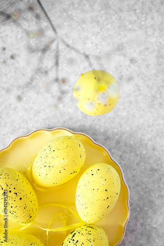 Bright yellow speckled Easter eggs on a decorative plate with spring ribbon