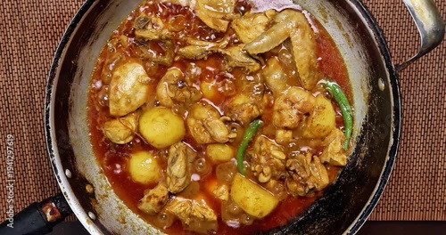 Chicken curry cooking sizzling bubbling in pan over hot flame top view flat lay top view