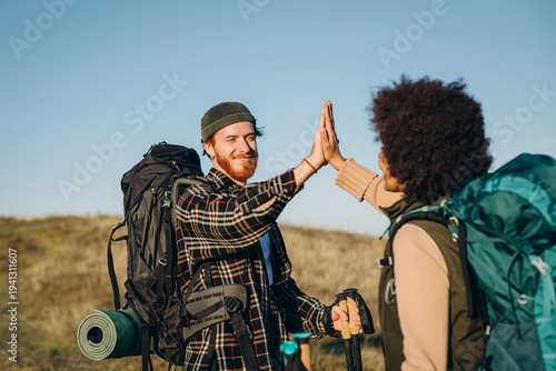 Photos Smiling redhead man gives high five to partner on hike at countryside