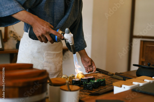 Foto Close Up Of Sushi Chef In Traditional Blue Uniform Using Blowtorch