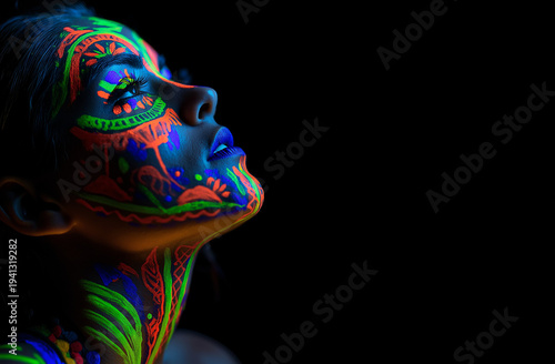 A woman with vibrant neon face paint looks up in a dark room