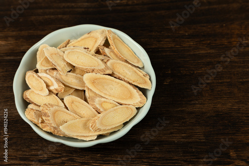 Schilderij op canvas Astragalus Slices in Celadon Bowl on Wooden Table