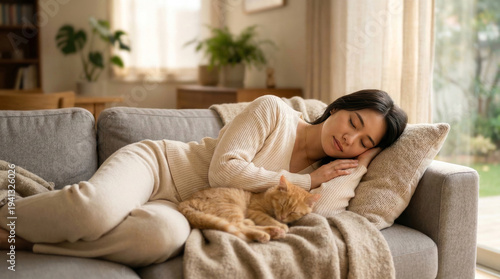 明るいリビングのソファーで猫と添い寝するルームウェア姿の女性の休息