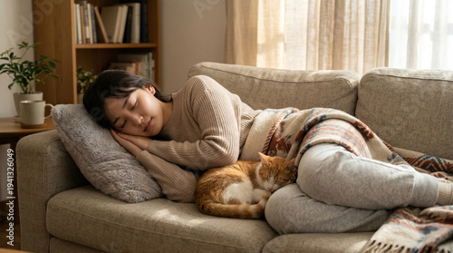 暖かいブランケットを掛けてソファーで猫と一緒に眠るリラックスした女性