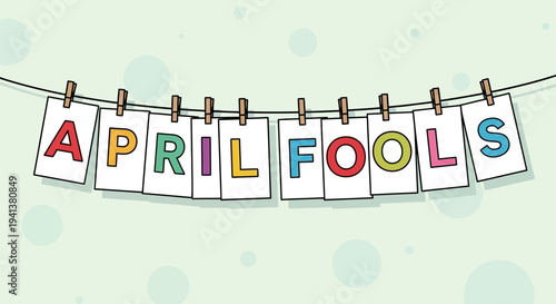 Colorful april fools cards on a string with clothespins hanging against a light green background with polka dots humorous holiday concept