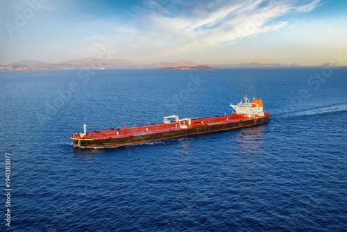 Aerial view of a heavy loaded crude oil tanker traveling off the coast during sunset time