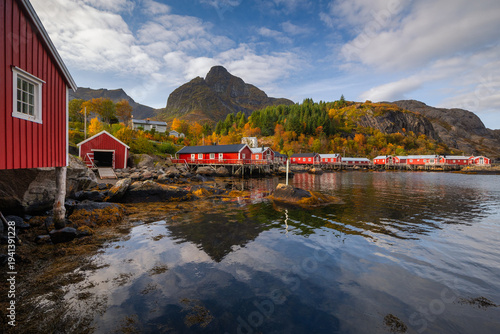 Historic architecture in Nusfjord, Lofoten. Peaceful autumn atmosphere, wooden cabins reflecting in the dark water surrounded by majestic mountains