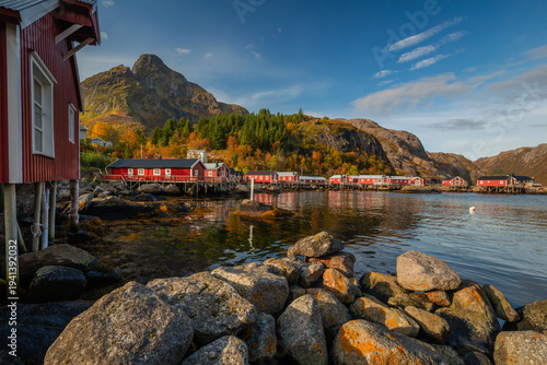 Historic architecture in Nusfjord, Lofoten. Peaceful autumn atmosphere, wooden cabins reflecting in the dark water surrounded by majestic mountains