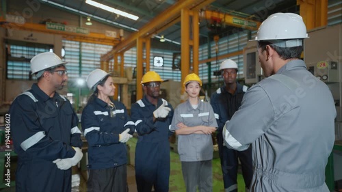 A team leader of multi-ethnic mechanical technicians or engineers explaining work details in a medium-sized automotive parts manufacturing factory, representing a globally standardized quality team