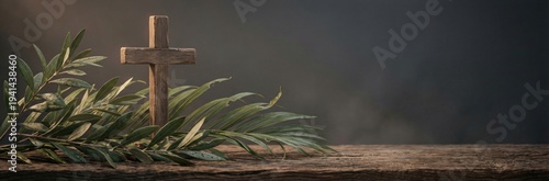 Small wooden cross with green palm frond and olive branches on a weathered wood surface. Religious background for Easter or Palm Sunday. Panoramic banner with copy space for text