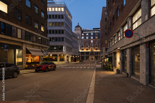 View of a quiet street illuminated by the soft glow of building lights contrasting with the deepening twilight sky, Oslo, Oslo, Norway.