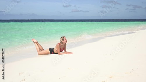 Happy young woman sunbathing in a swimsuit on a sandy beach on a tropical island