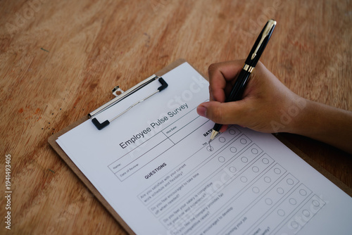 Hand ticking checkbox on employee pulse survey form for workplace feedback and corporate culture concept