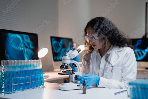 Obraz na plátne Female scientist wearing glasses and gloves working with a microscope in a labor