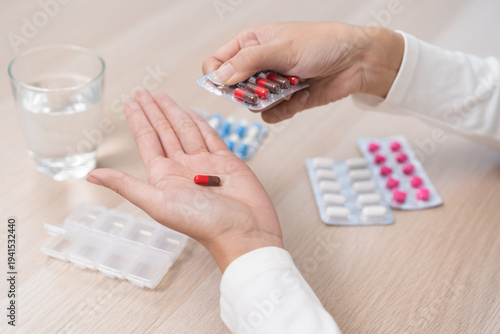 Sick ill asian young woman, girl hand taking tablet pill capsule out from blister pack, painkiller medicine from stomach pain, head ache, pain for treatment, take drug or vitamin at home, health care.
