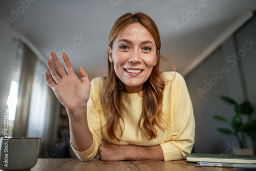 Foto Woman waving hello connecting on video call from home
