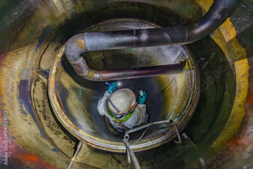 Top view male climbs down the stairs into the tank grease chemical area, confined space safety sling