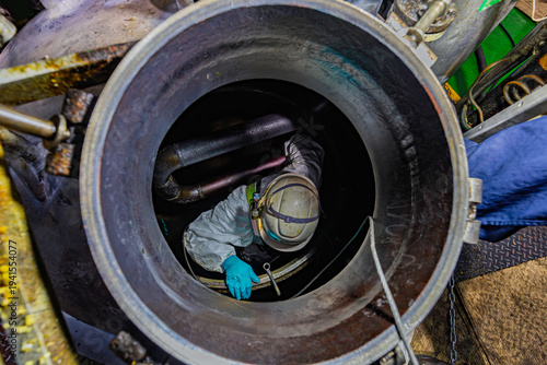 Top view male climbs down the stairs into the tank grease chemical area, confined space safety sling