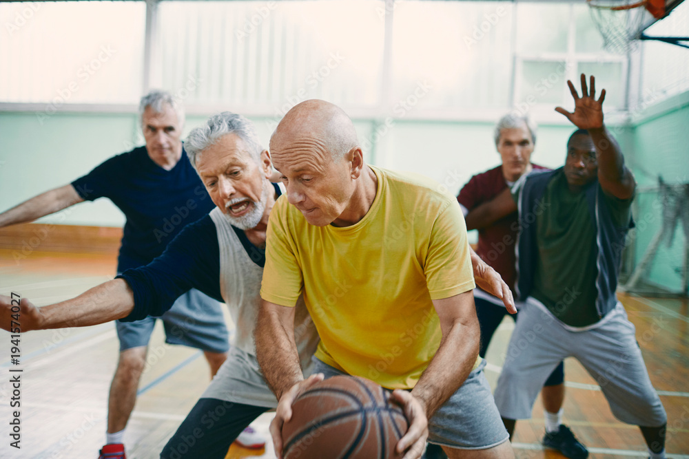 Fototapeta premium Senior men playing competitive basketball in indoor gym