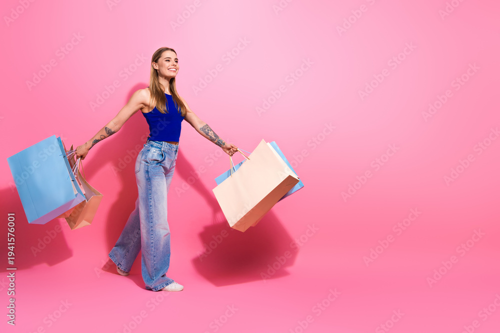 Fototapeta premium Young woman shopping with colorful bags on pink background in casual stylish fashion shoot